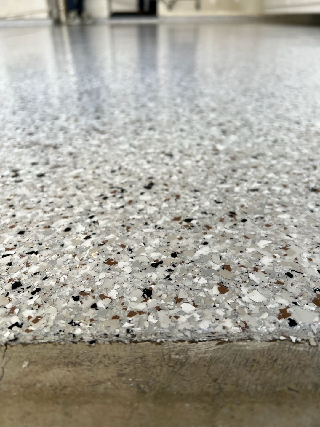 Close-up of a shiny epoxy floor featuring gray and speckled textures in a modern space.