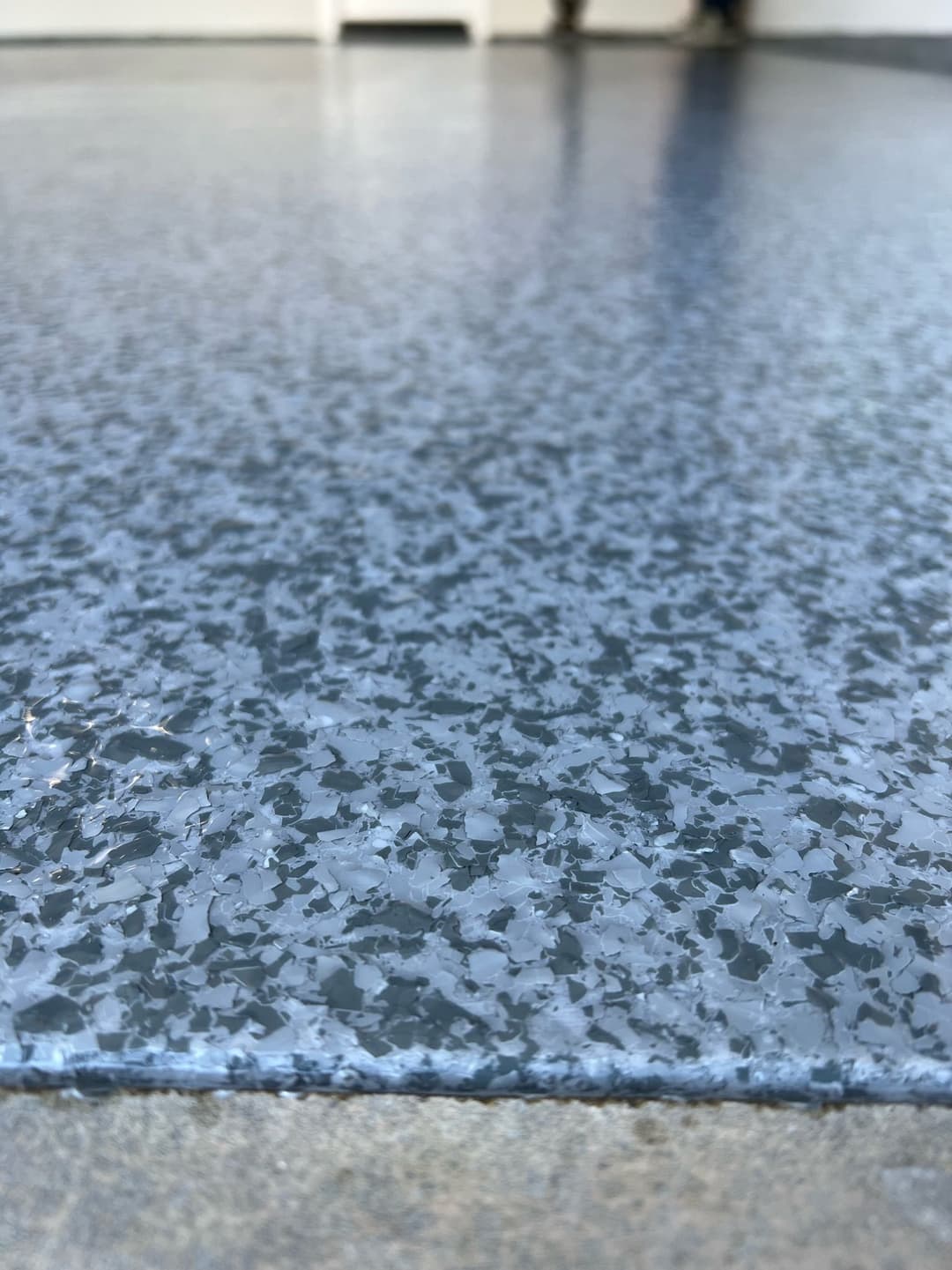 Close-up of a textured blue-gray epoxy floor surface with decorative flakes.