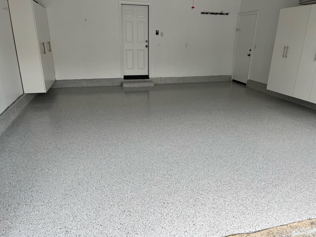 Modern garage with freshly coated epoxy flooring and white storage cabinets.