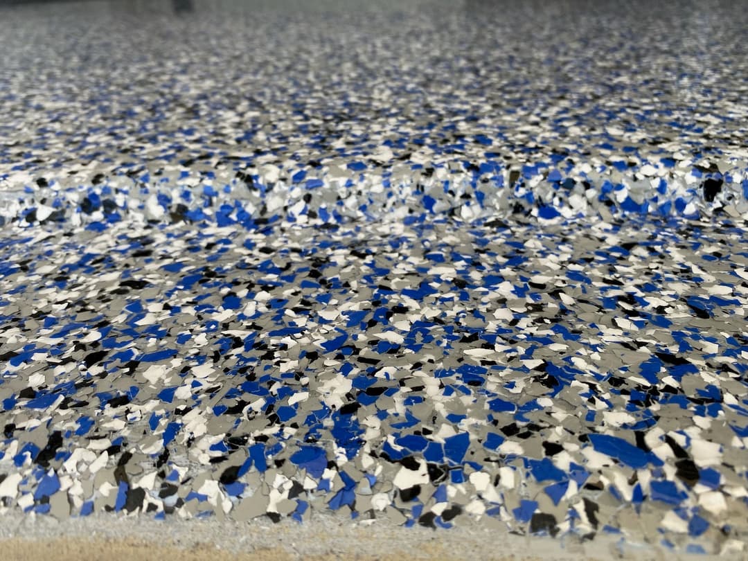 Industrial epoxy flooring with blue and silver speckles, showcasing a textured surface.