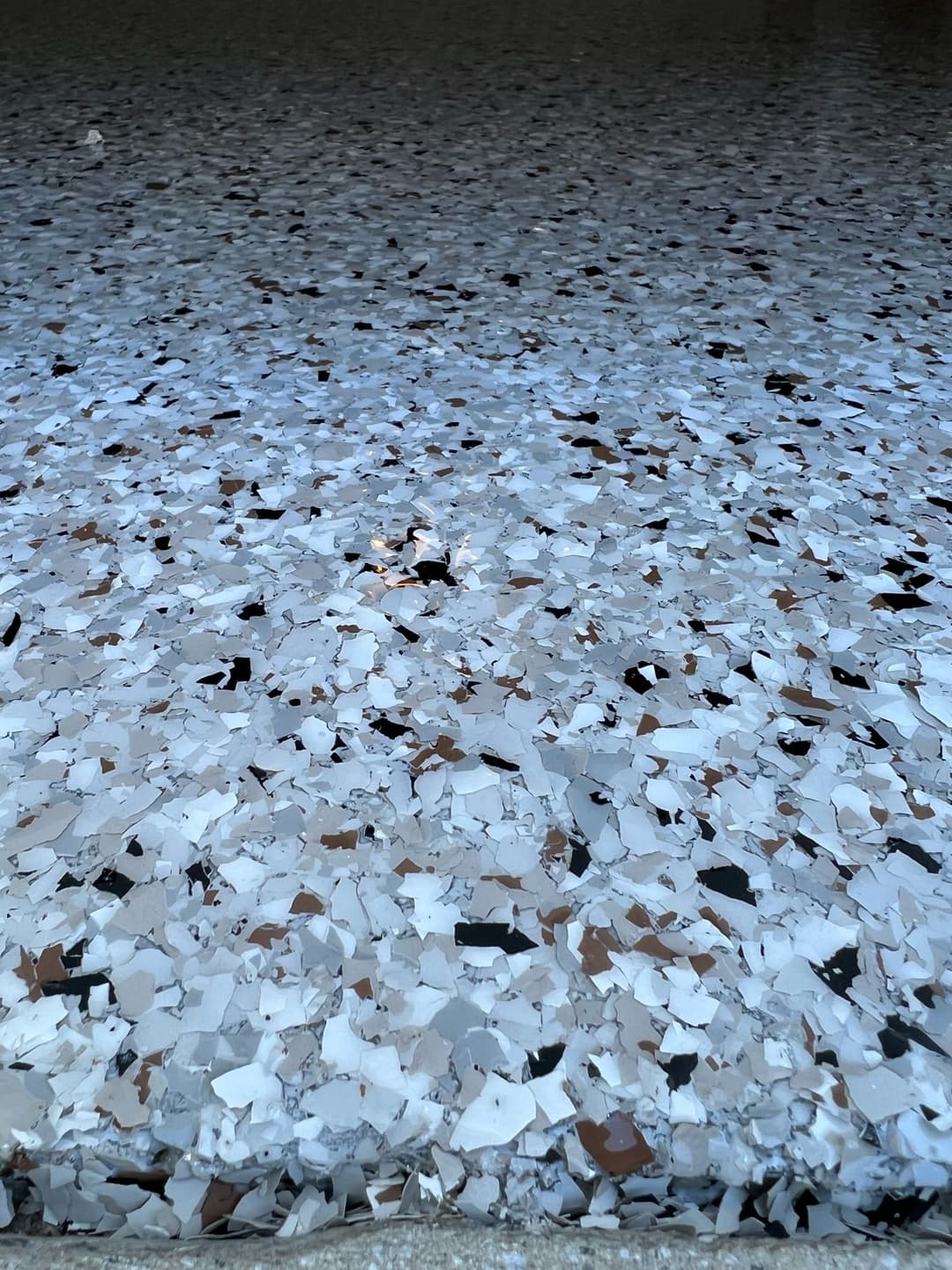 Multicolored epoxy floor with white, black, and brown chips, showcasing texture and detail.