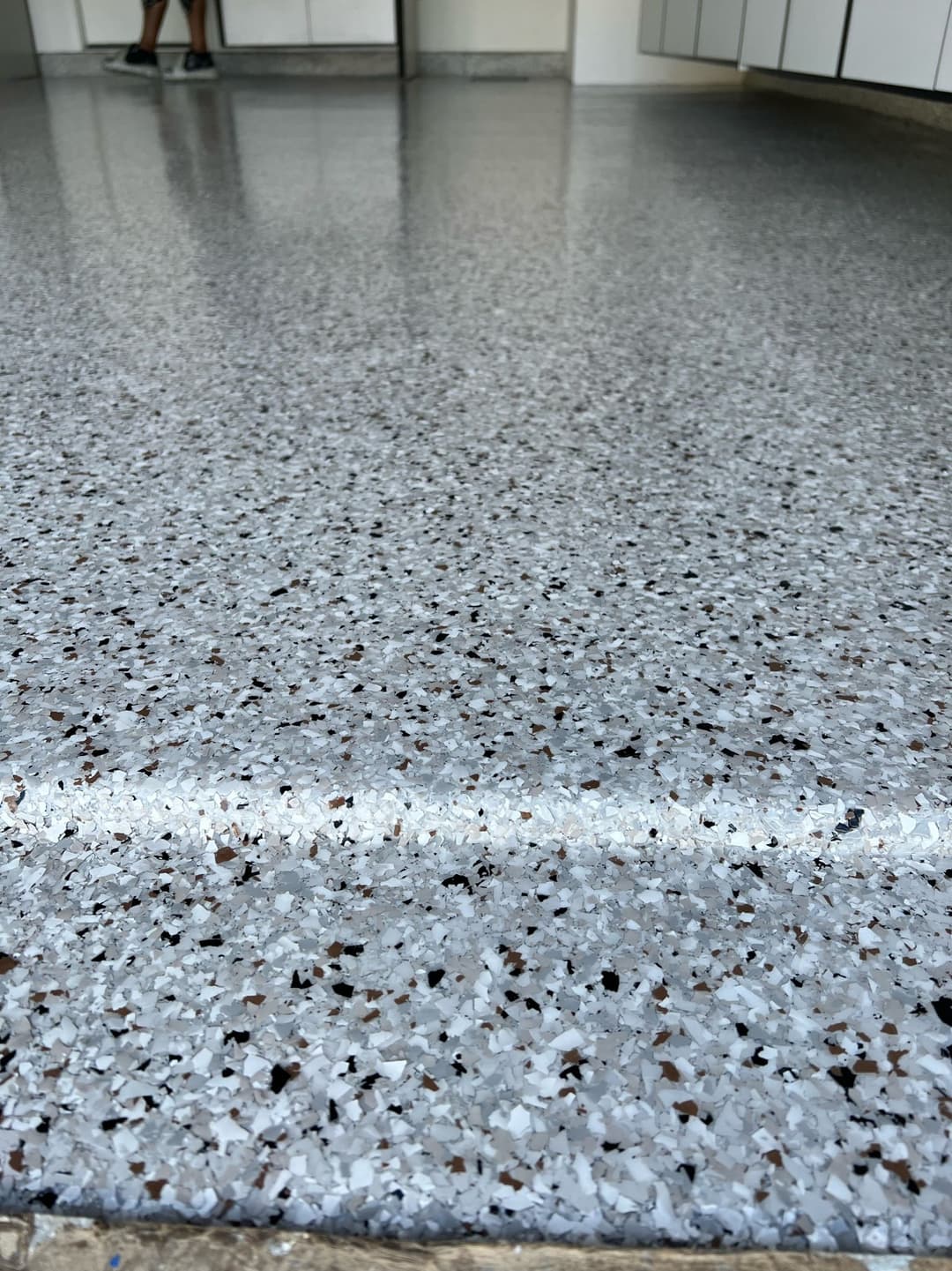 Glossy epoxy floor with gray and white speckles in a bright indoor space.
