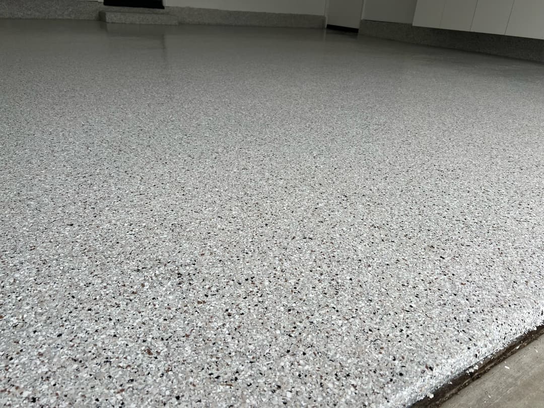 Epoxy-coated garage floor with a smooth, glossy finish and decorative flakes.