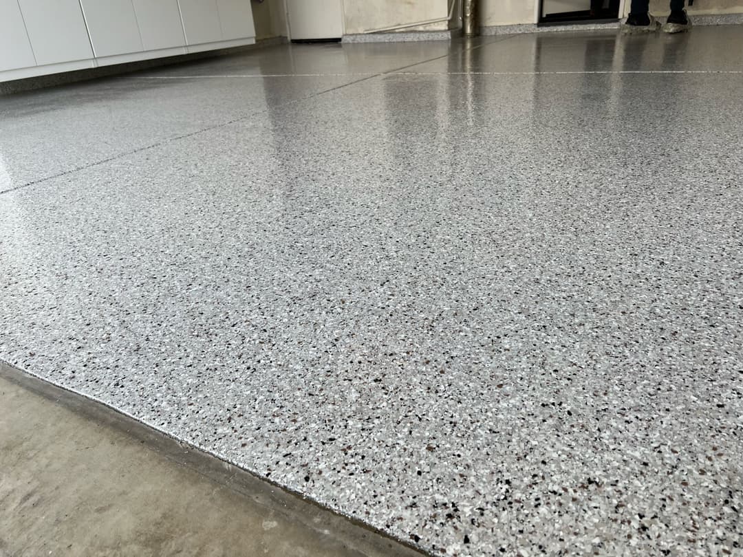 Epoxy-coated floor with a speckled gray finish in a modern interior space.