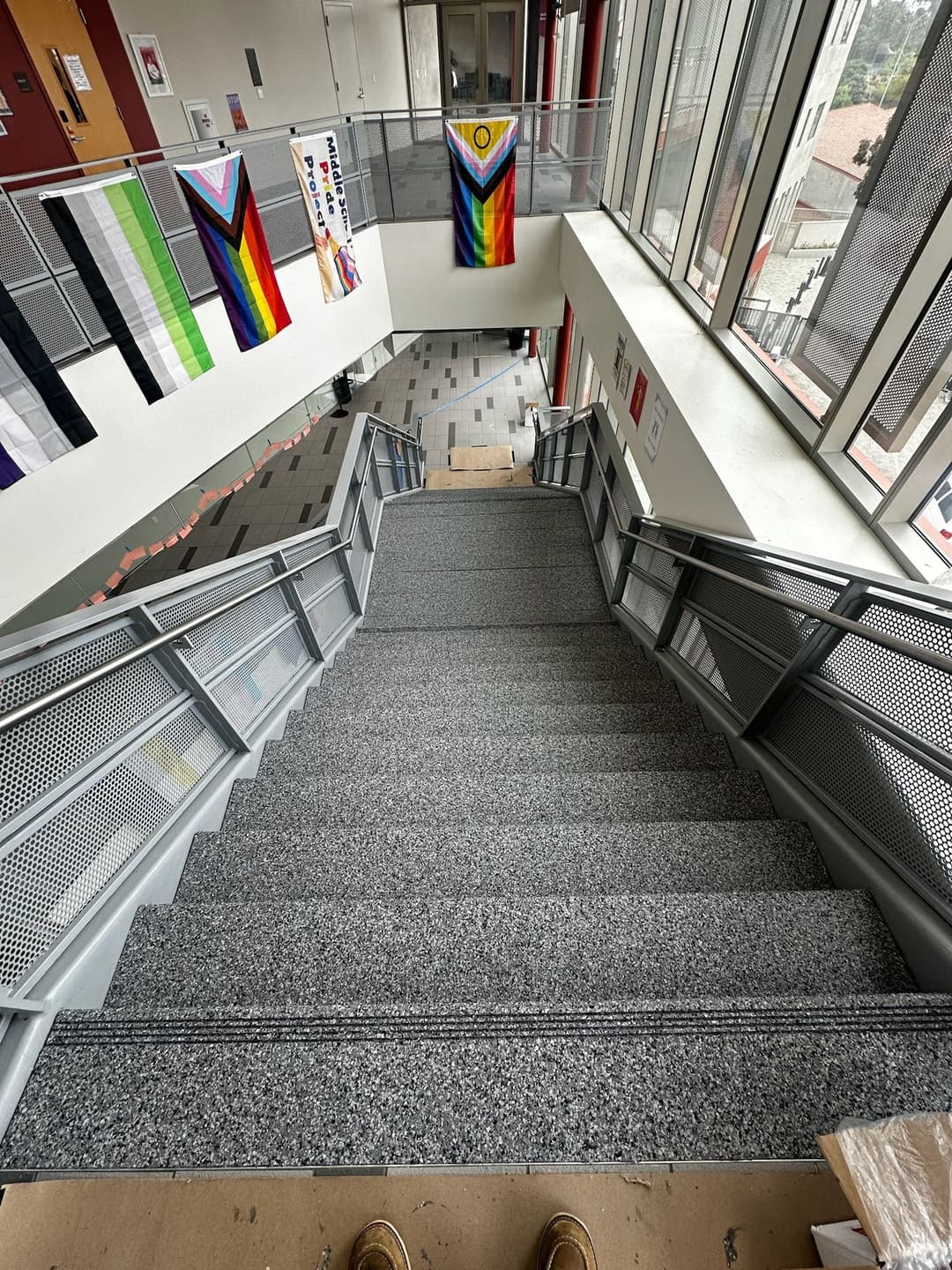 View of a staircase with colorful flags hanging on walls, highlighting inclusive atmosphere.