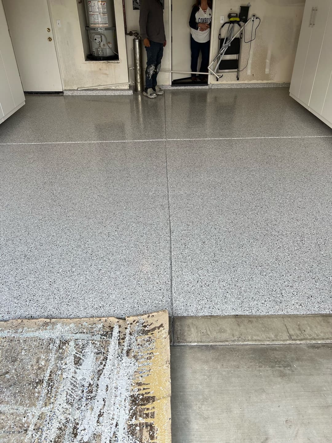 Newly coated epoxy garage floor with one person standing near cleaning equipment.