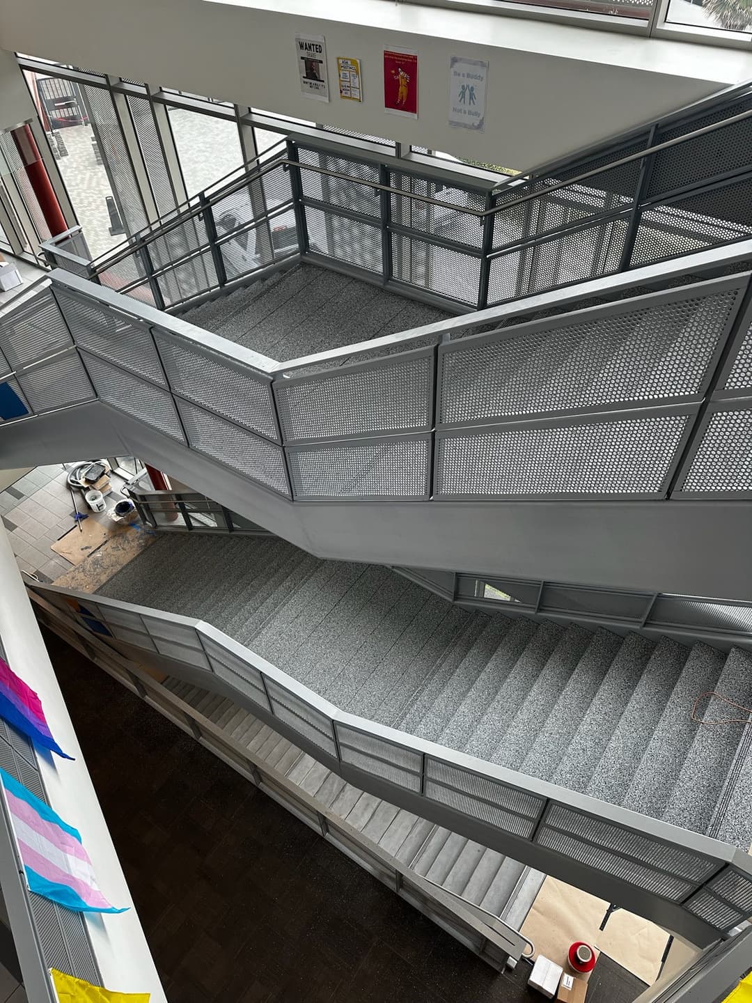 Interior view of a modern multi-level staircase with mesh railings and natural light.