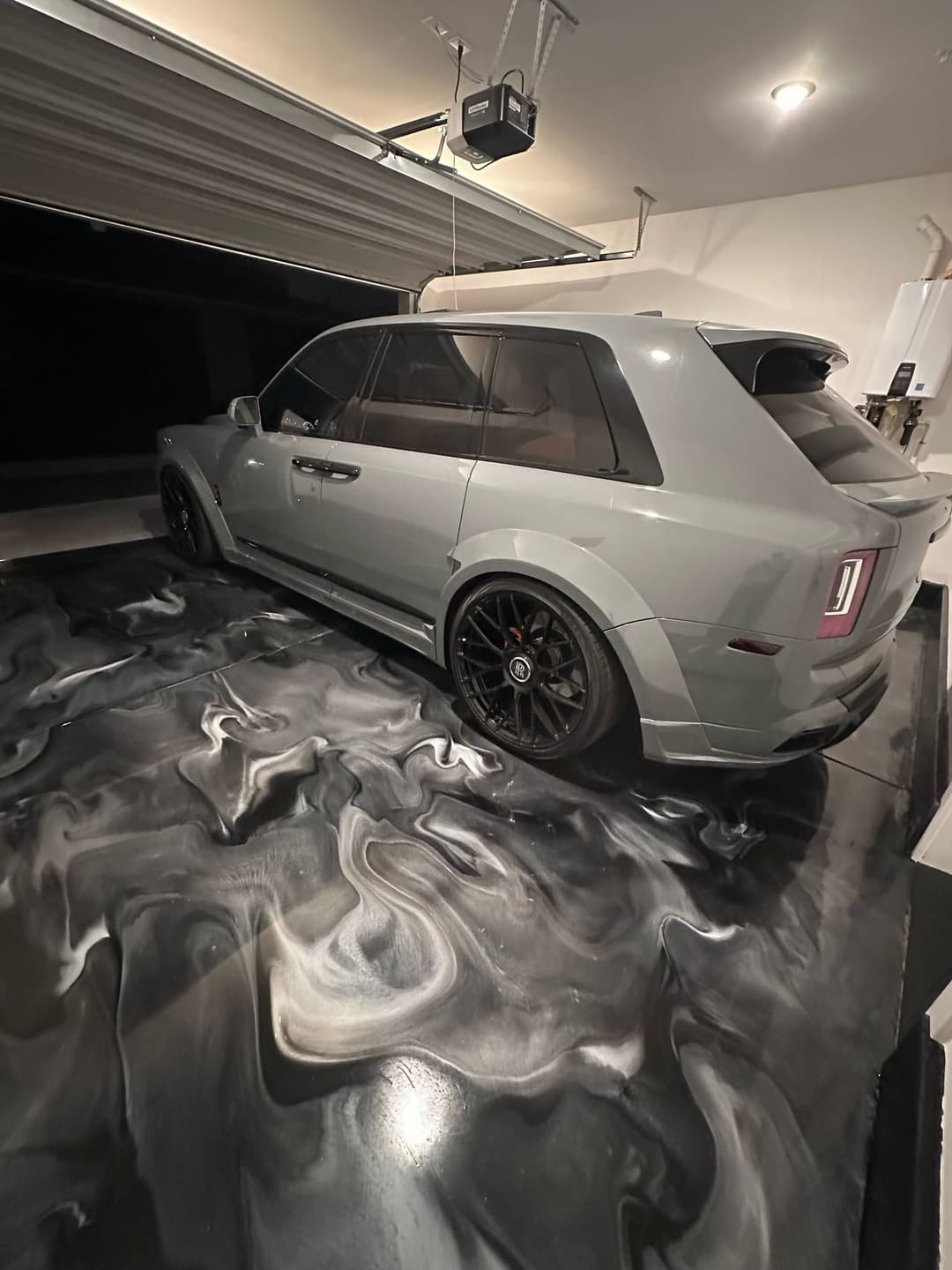 Luxury SUV parked in a modern garage with a unique marble floor design.