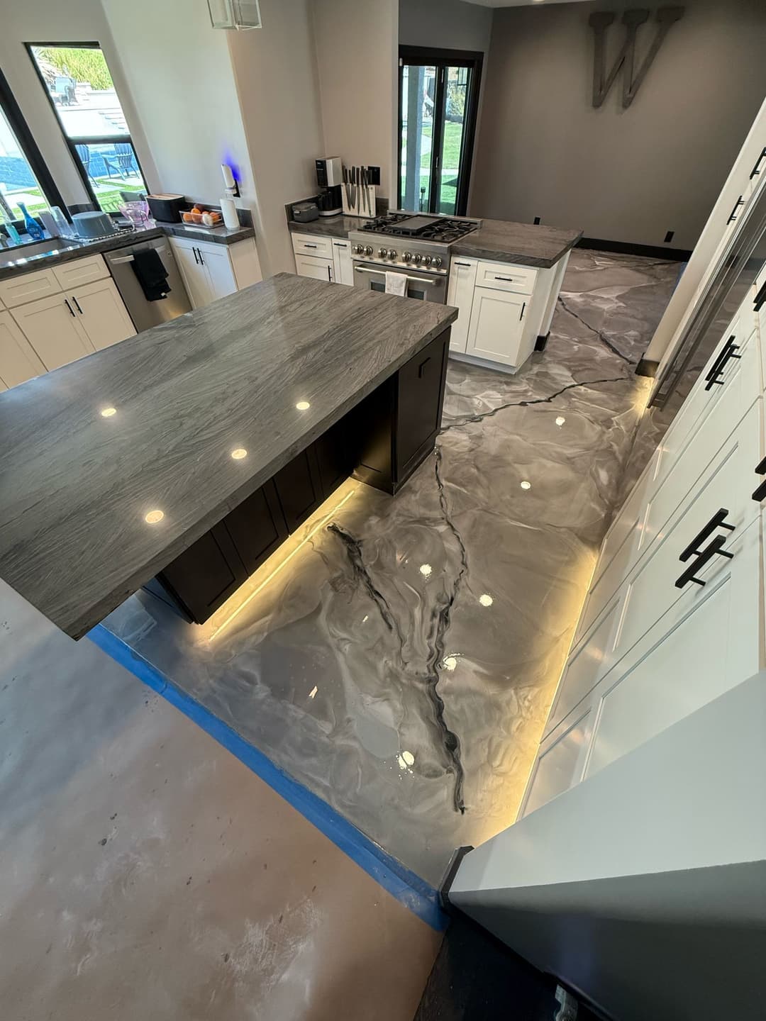 Modern kitchen with stone countertops and illuminated marble flooring details.