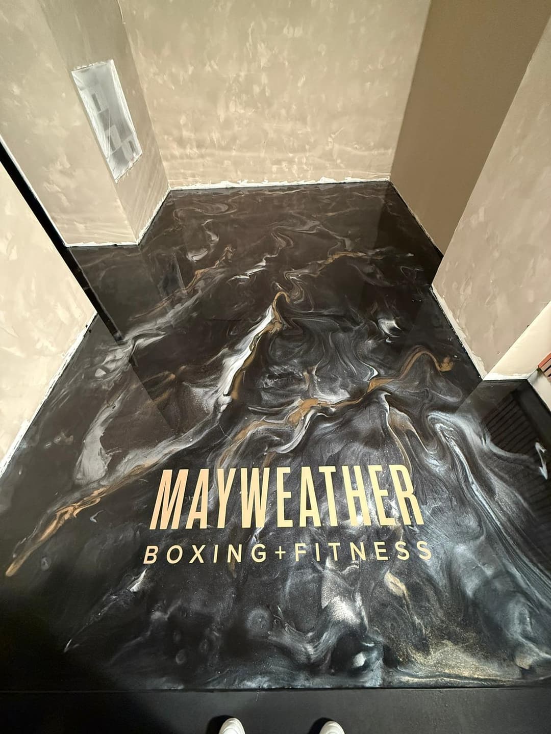 Mayweather Boxing + Fitness logo on a black and gold marbled floor design.