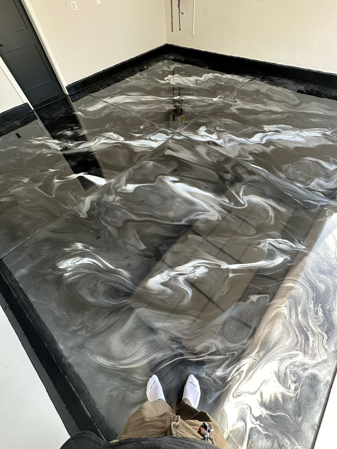Epoxy resin floor with a striking black and silver marble effect, viewed from above.