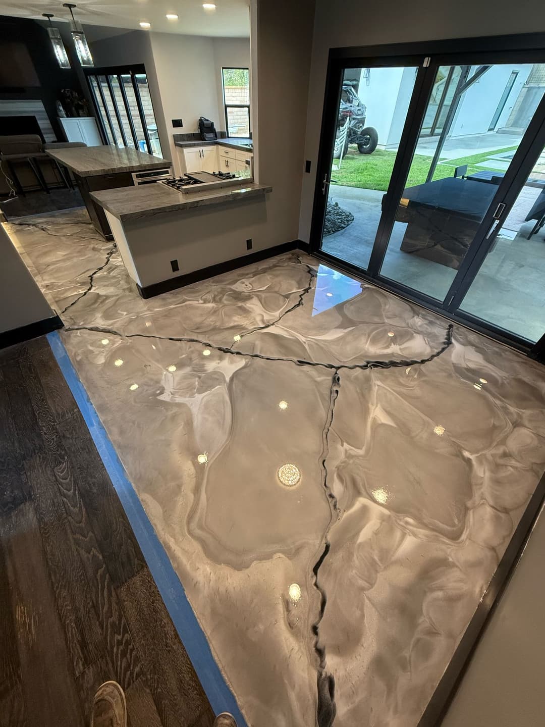 Elegant epoxy resin floor with marble-like design and contrasting black lines in modern kitchen.
