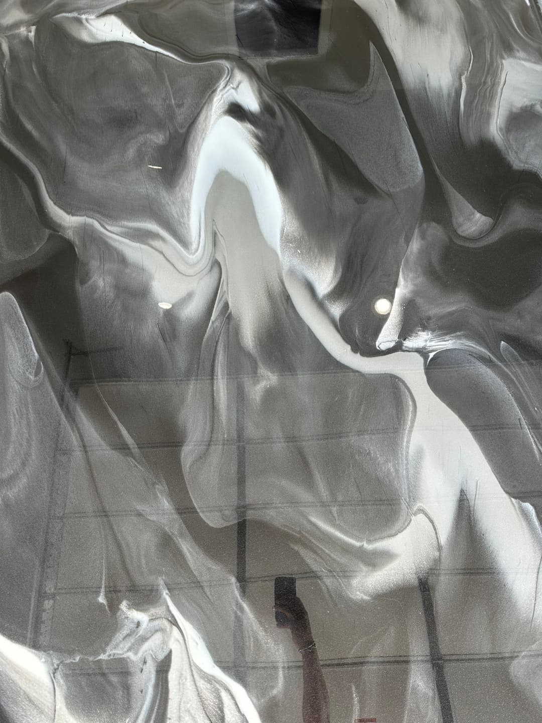 Abstract gray and white marble surface with fluid swirls and reflections.