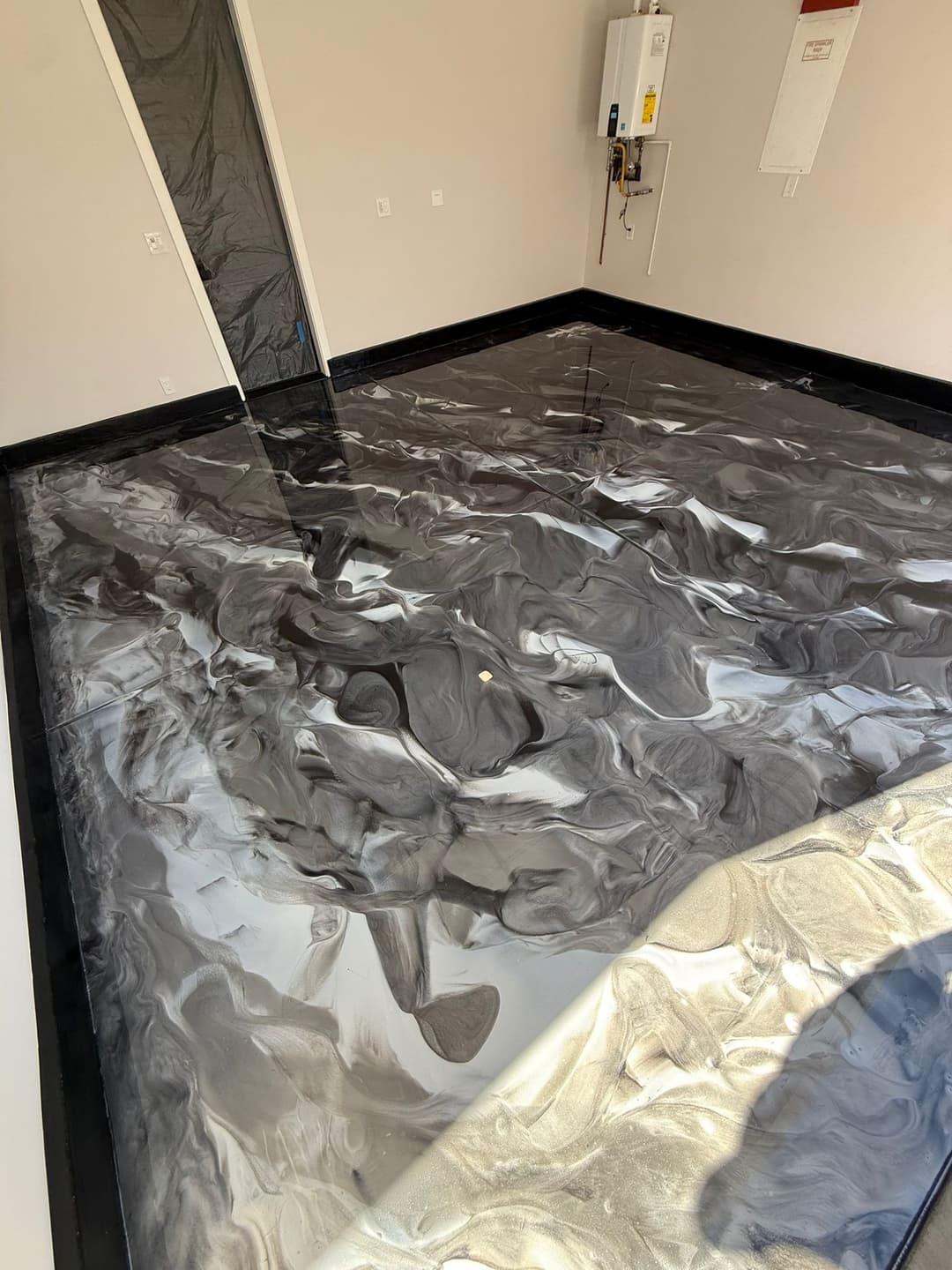 Epoxy resin floor with a swirling black, white, and gray design in a modern room.