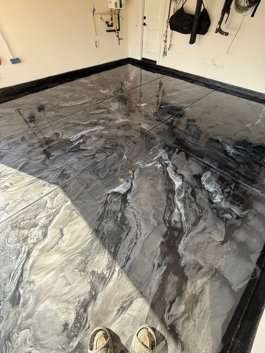 Epoxy garage floor with a unique black and gray swirling design, freshly finished.