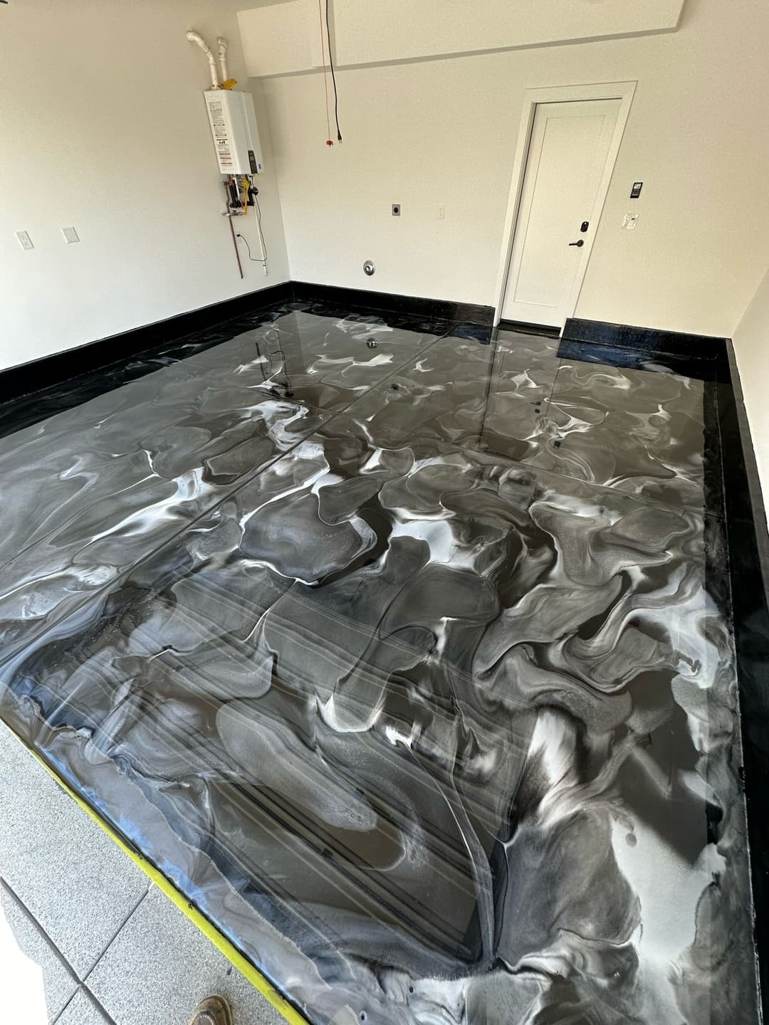 Modern epoxy-coated garage floor featuring a sleek black and white marble design.