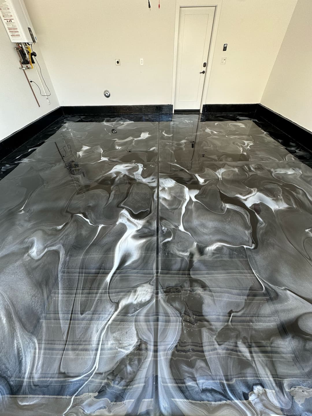 Luxurious black and white epoxy floor in a modern garage, featuring a swirling design.