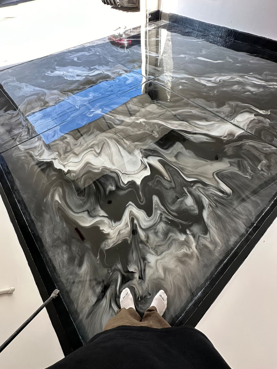 Person standing above a newly created black and white epoxy resin floor.