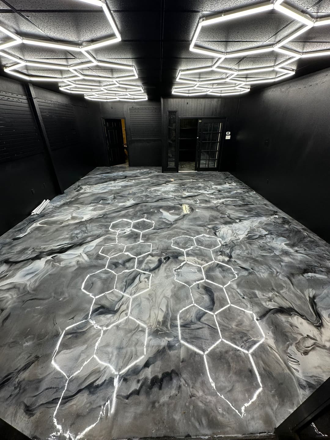 Stylish black and gray marble floor with hexagon patterns under modern geometric lighting.