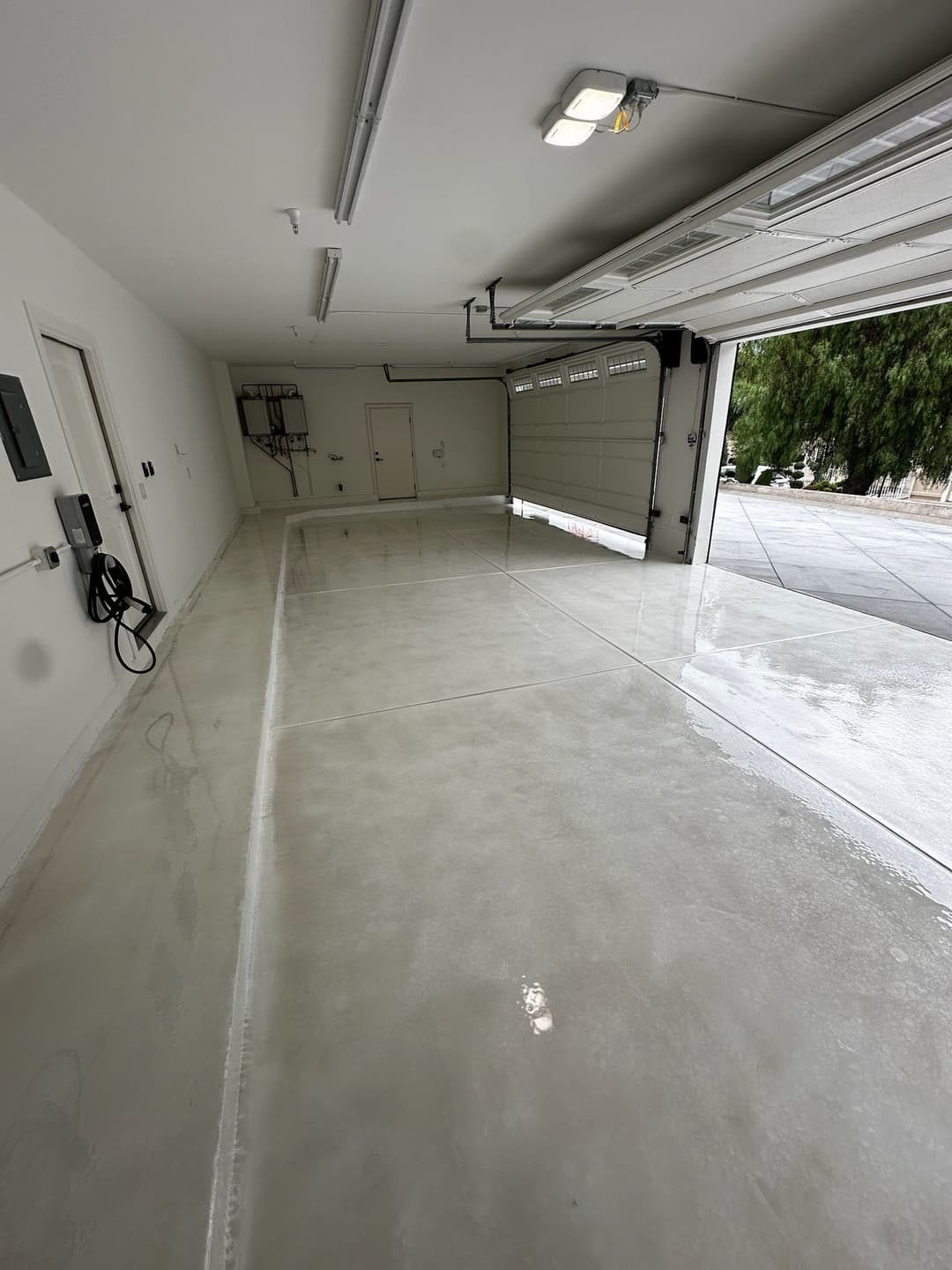 Clean, polished garage with bright lighting and open door, showcasing ample space.