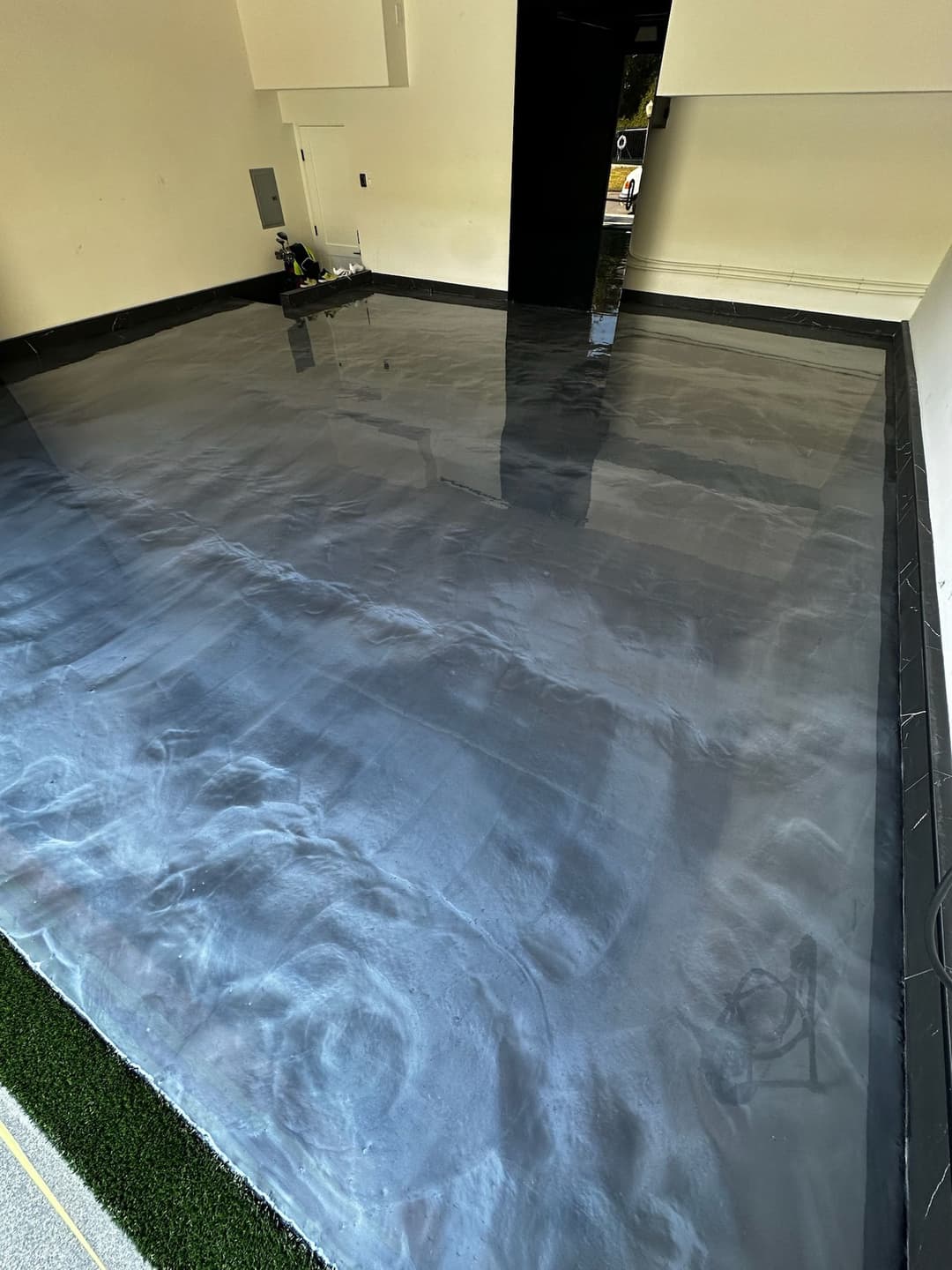 Glossy black epoxy floor in a modern interior space, reflecting light and textures.
