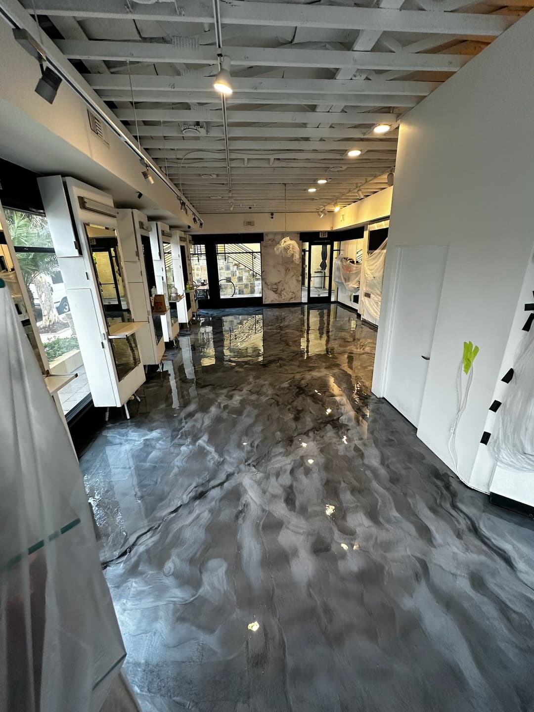 Modern interior with polished black concrete floor, bright lighting, and minimalist design.