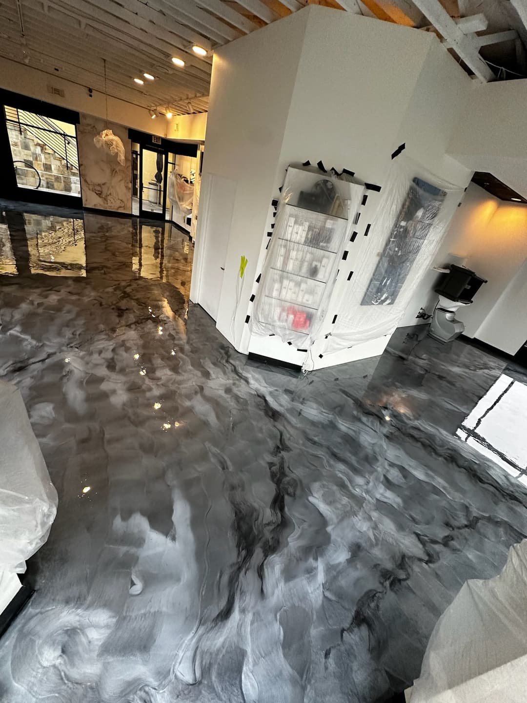 Modern art gallery interior with polished black and white epoxy floor, under renovation.