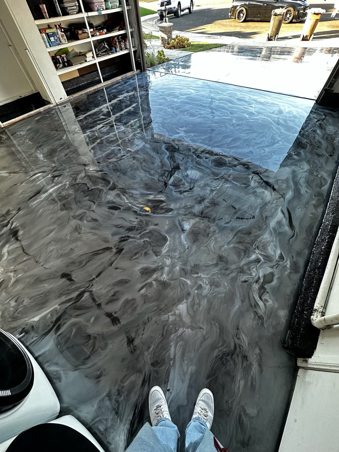 epoxy resin floor with a swirling gray design, person standing on it in a garage setting