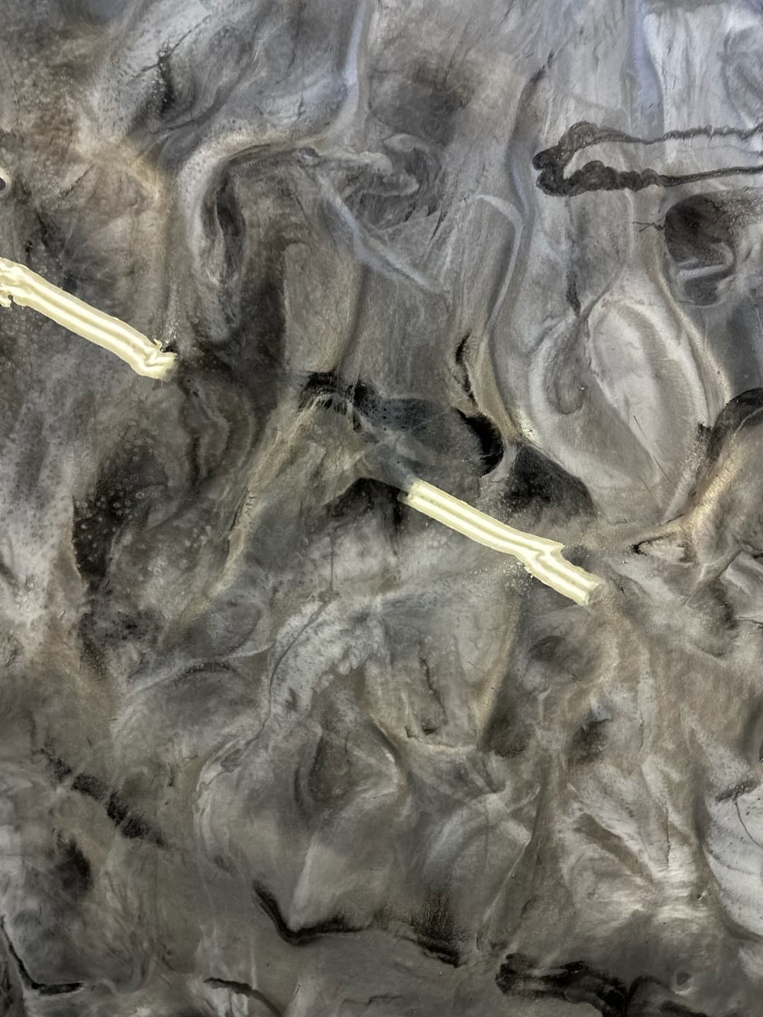 Abstract gray and black textured surface with white lines creating dynamic patterns.