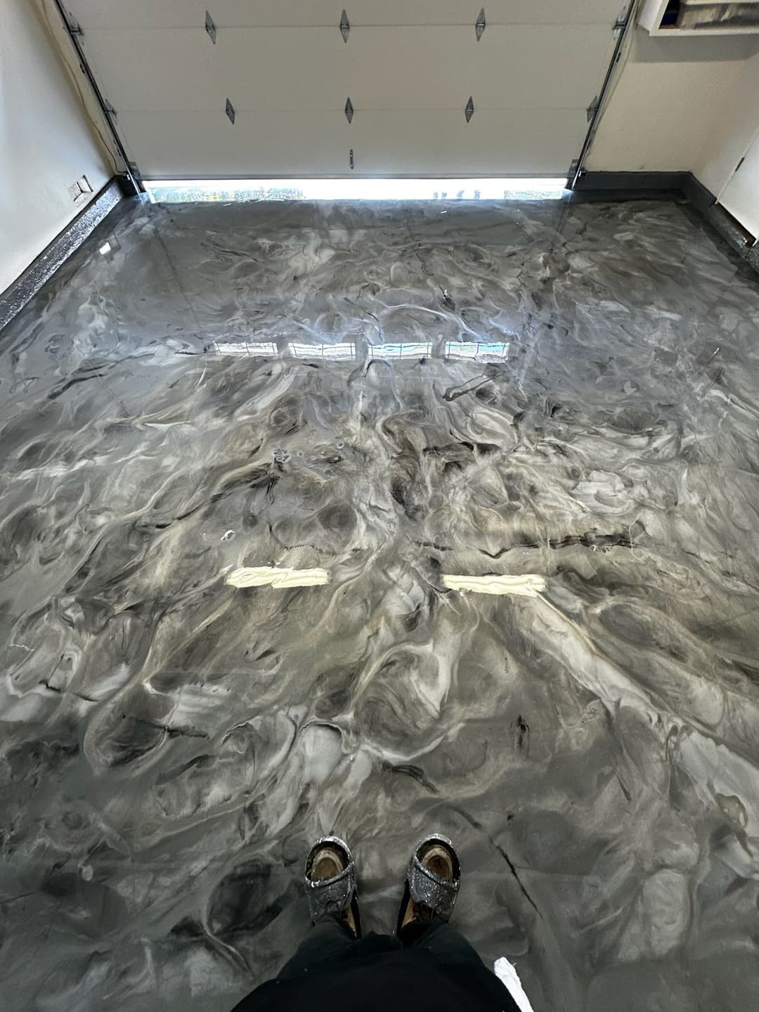 Polished epoxy garage floor with swirled gray and black patterns, viewed from above.