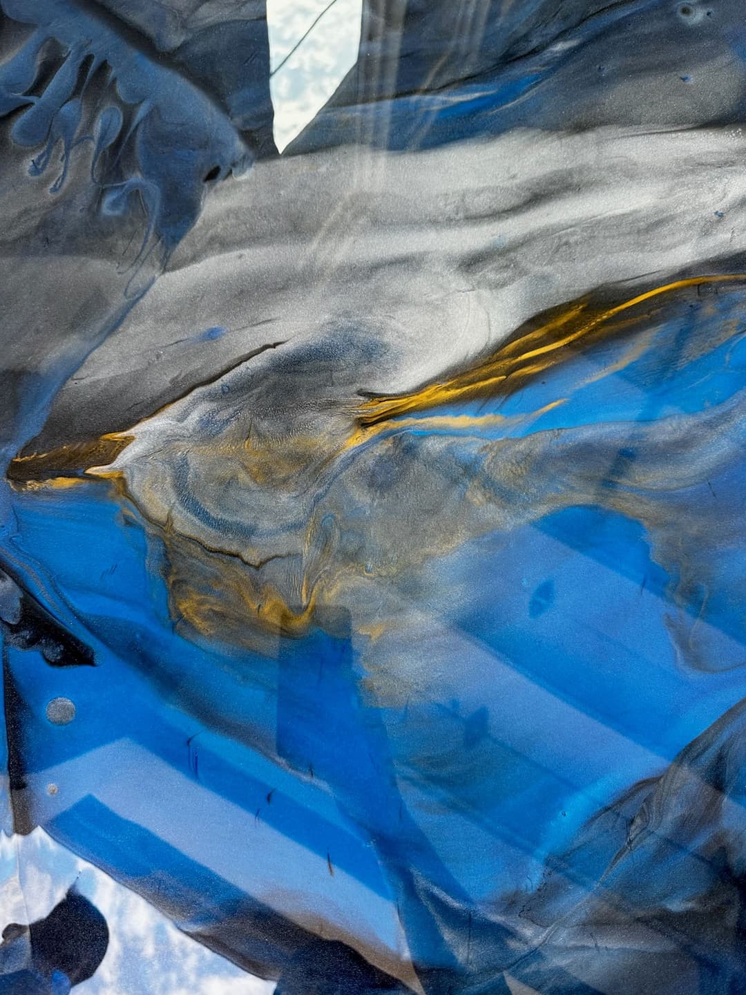 Abstract blue and gold fluid art with swirling patterns and textures.
