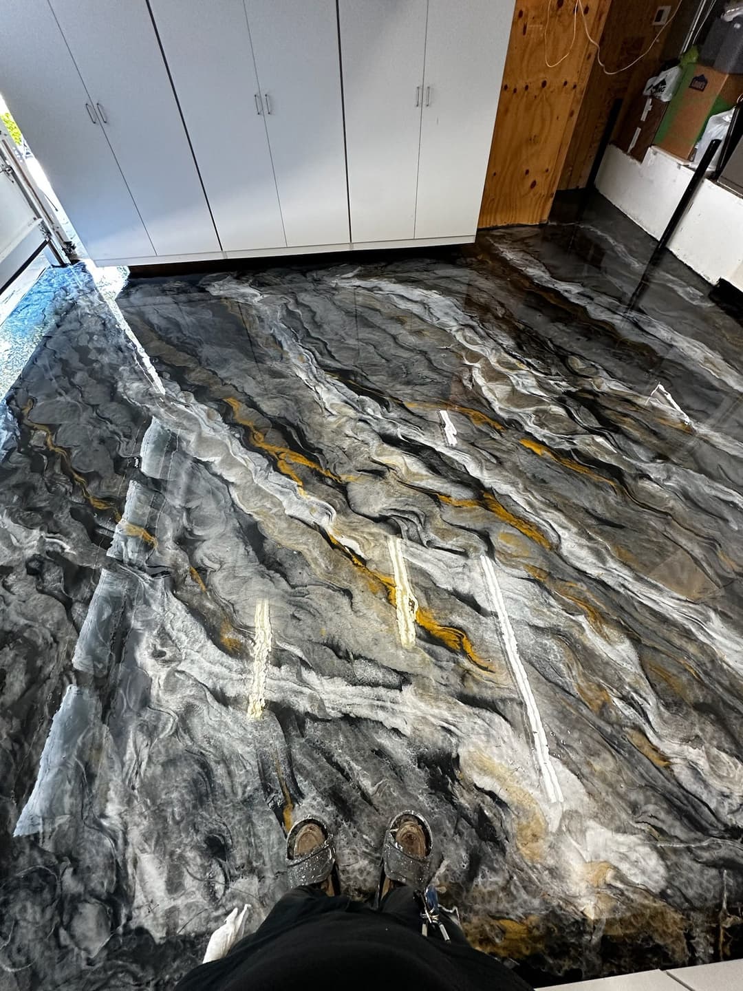 Glossy black and gold epoxy floor with a unique abstract design in a garage space.