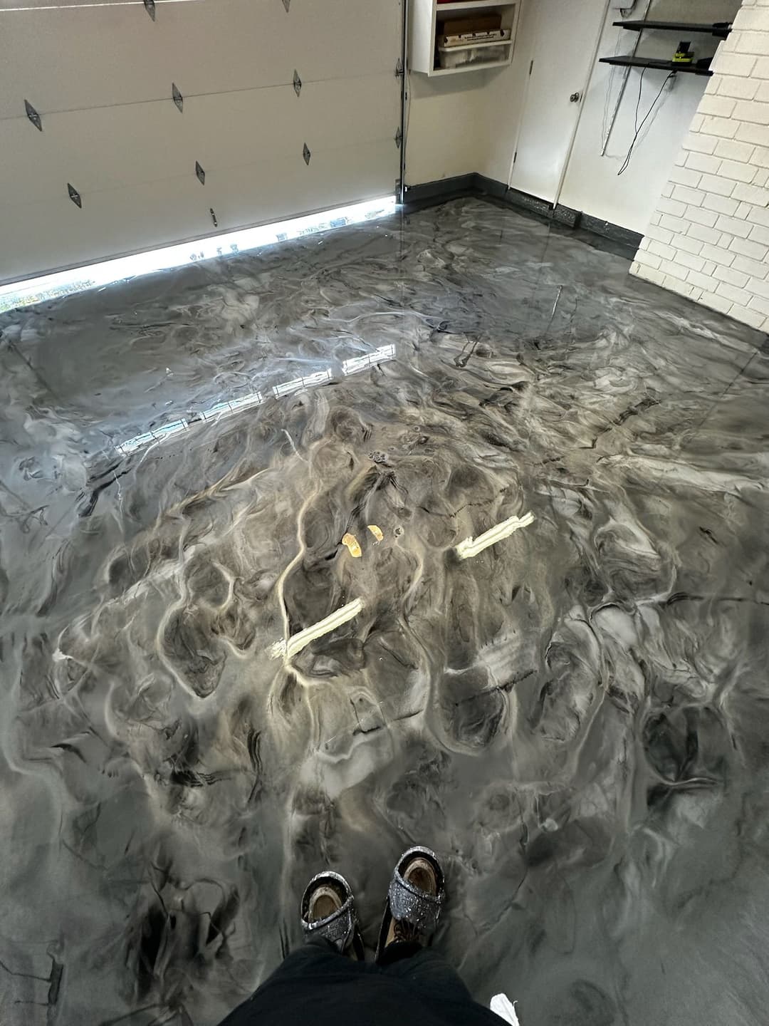 Glossy epoxy garage floor with unique swirl patterns and cables on the surface.