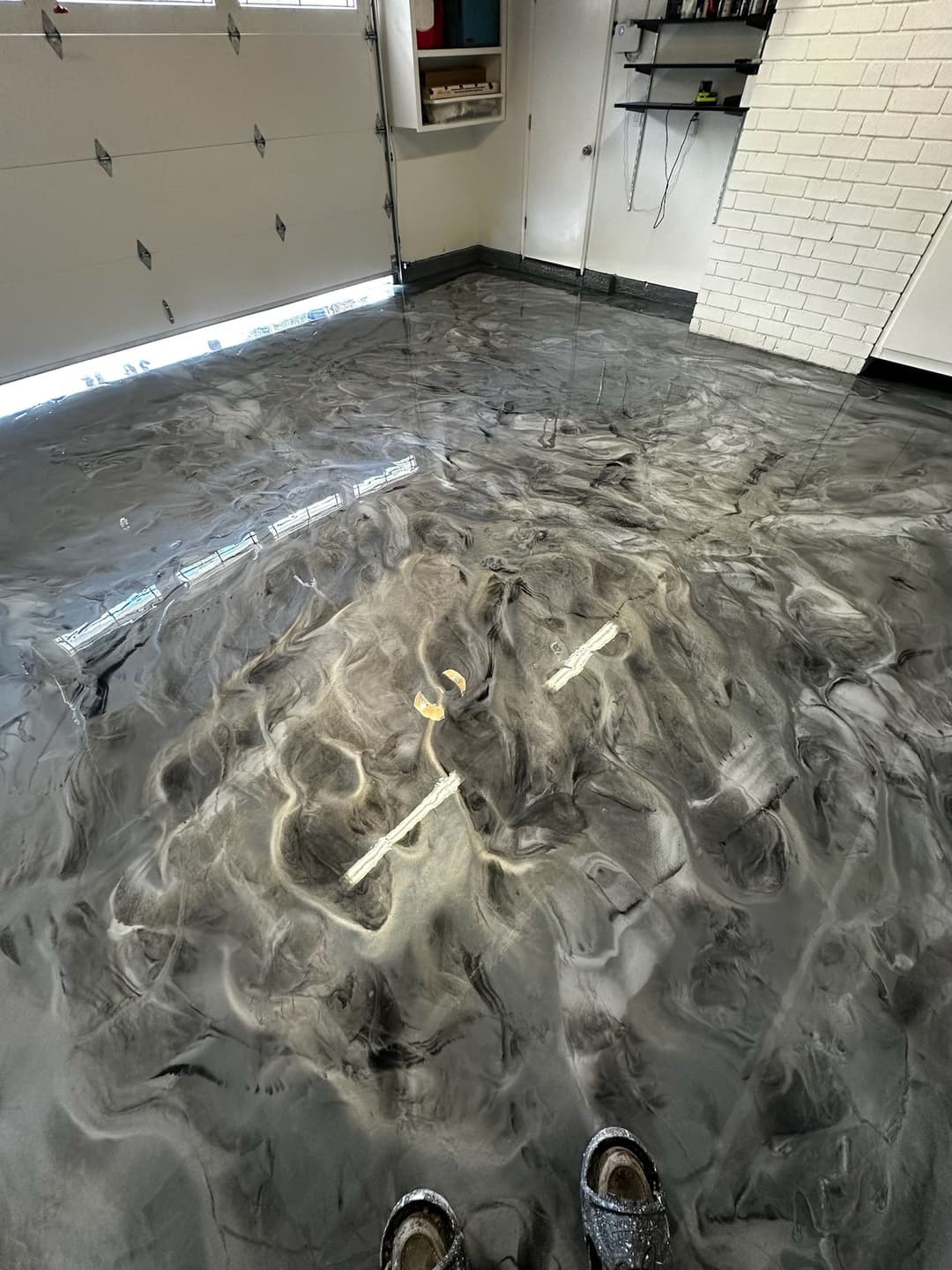 Shiny epoxy floor surface with swirling gray patterns in a garage setting.