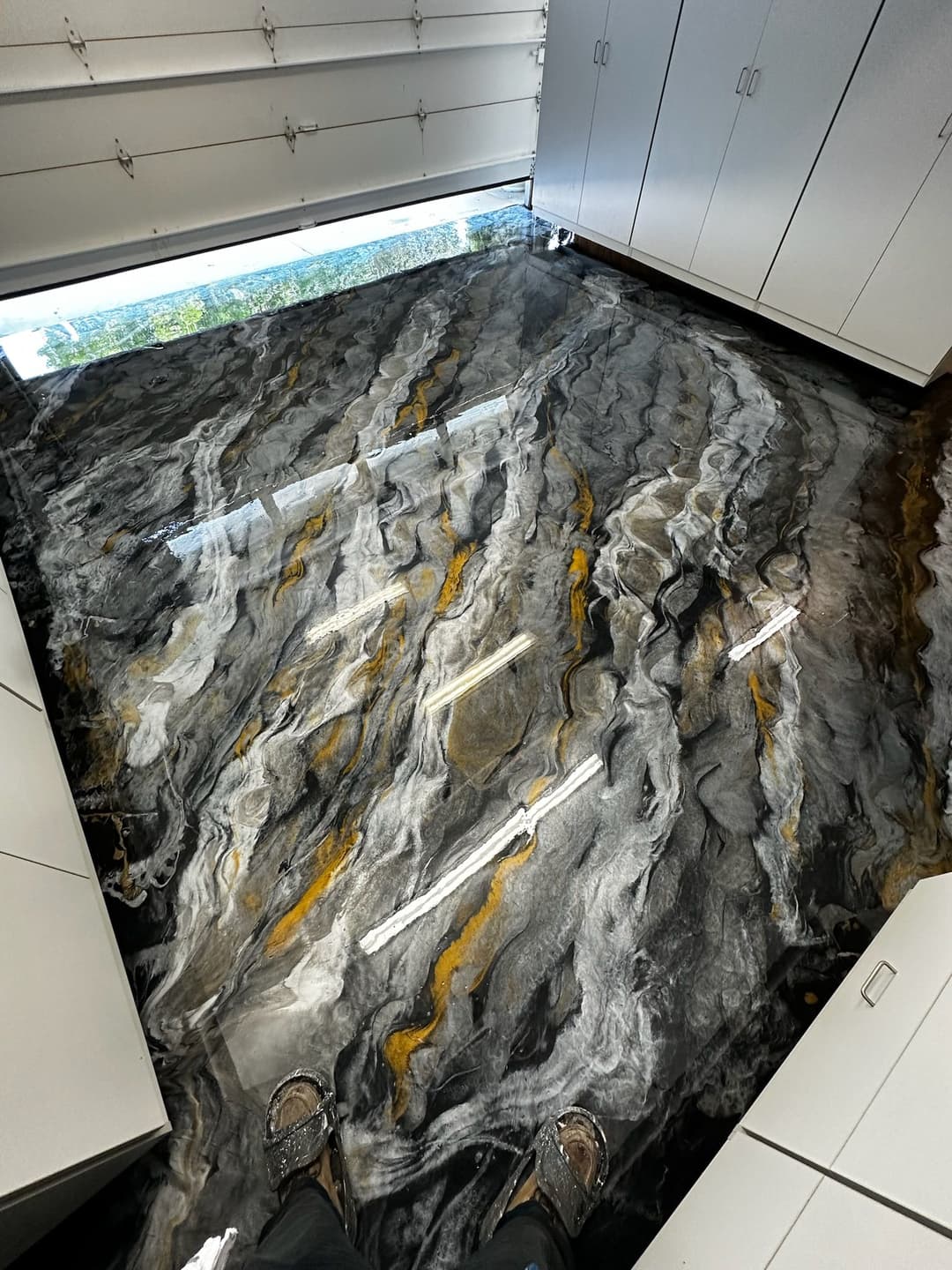Luxury epoxy floor with swirling black, gray, and gold patterns in a modern workspace.