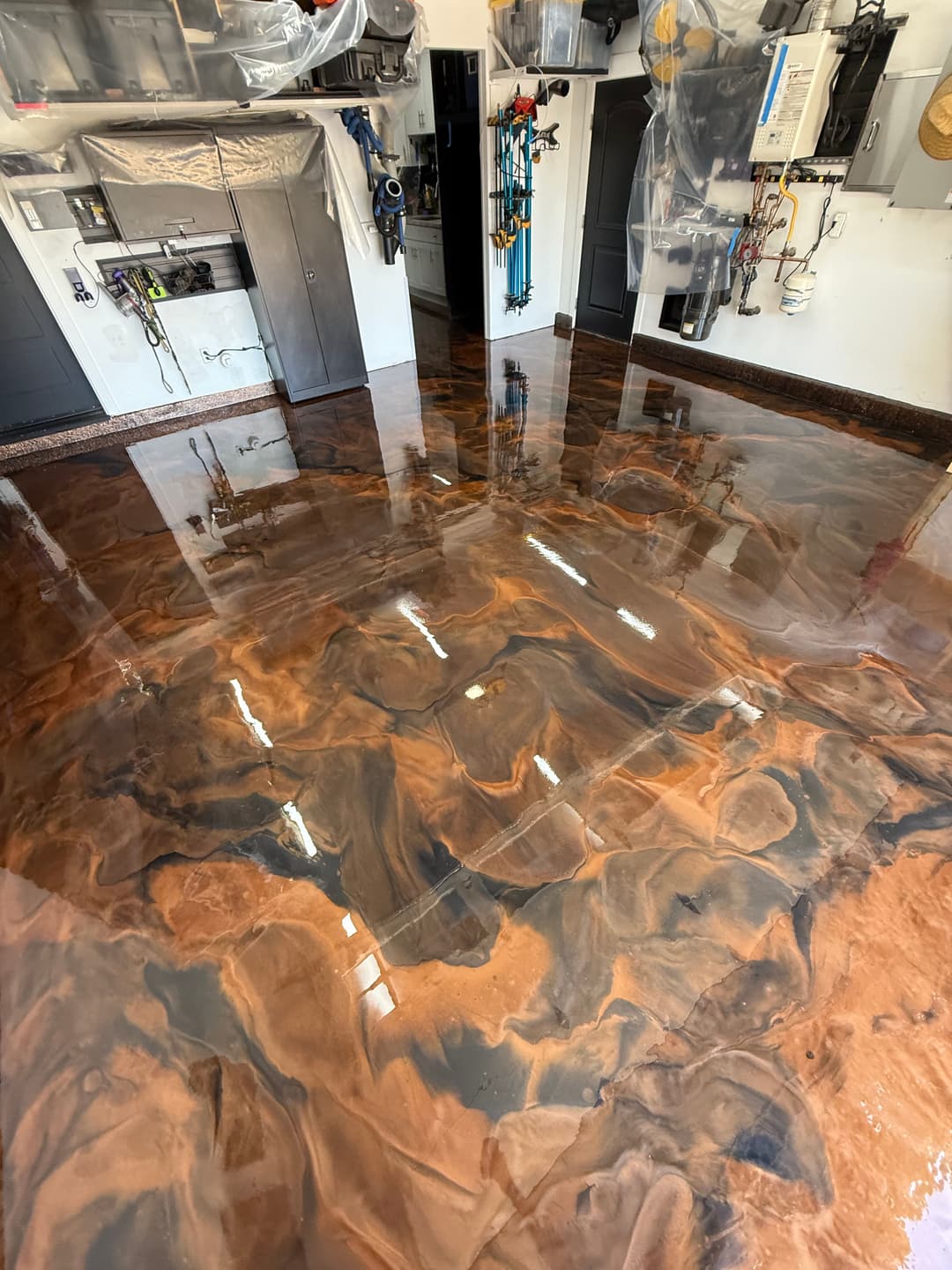 Epoxy resin floor with swirling brown and black patterns in a garage setting.