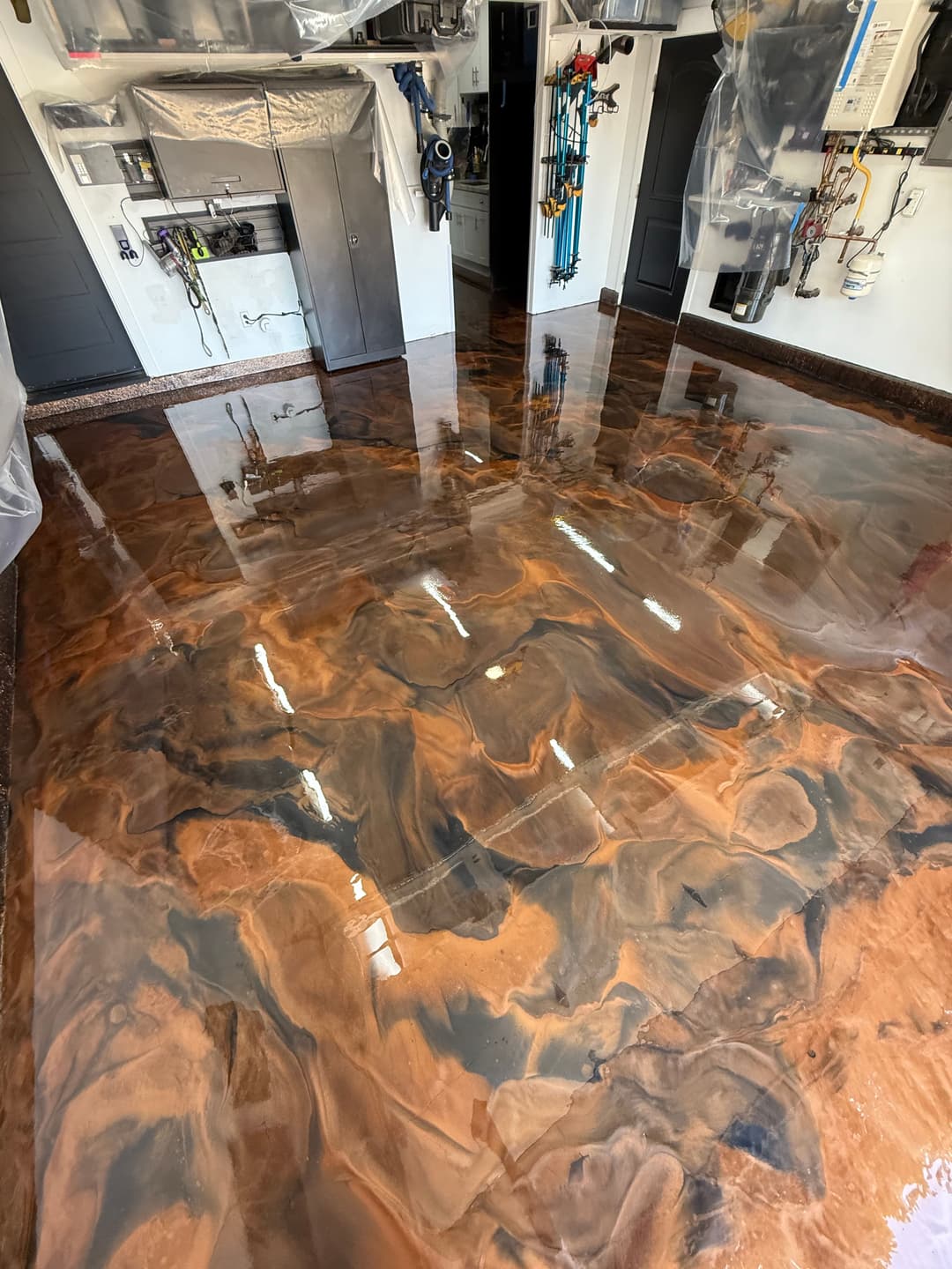 Epoxy resin floor with a swirling brown and black design in a garage setting.