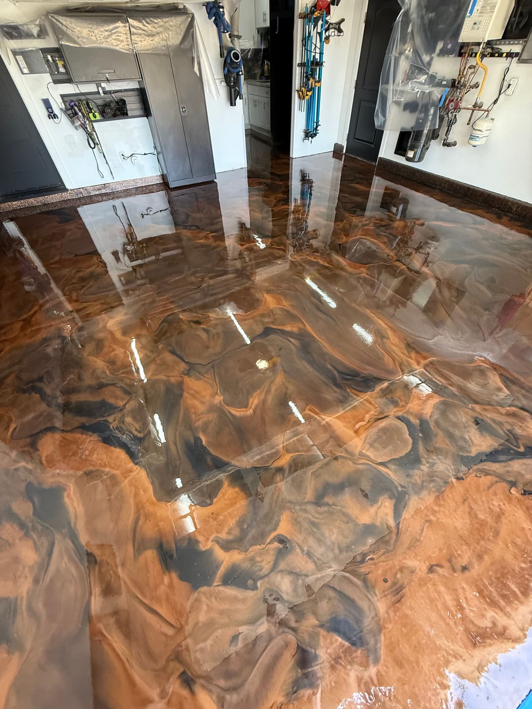 Glossy epoxy floor with brown and black swirls in a garage setting, showcasing modern design.