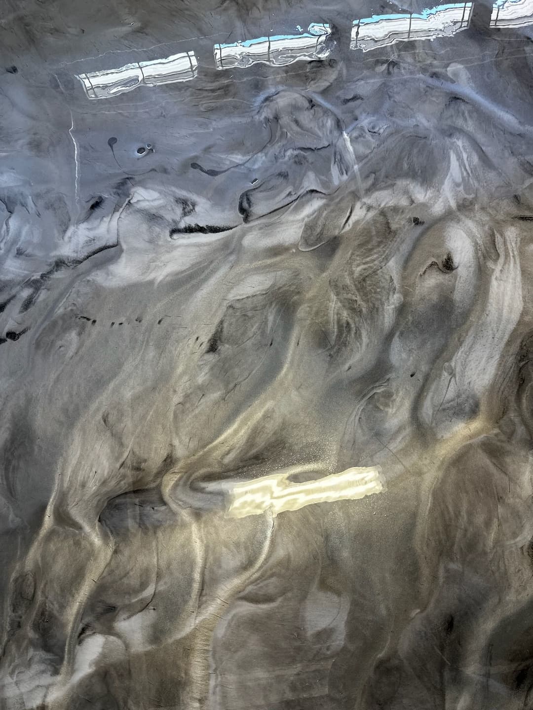 Abstract gray and white marbled surface with reflective light patterns.