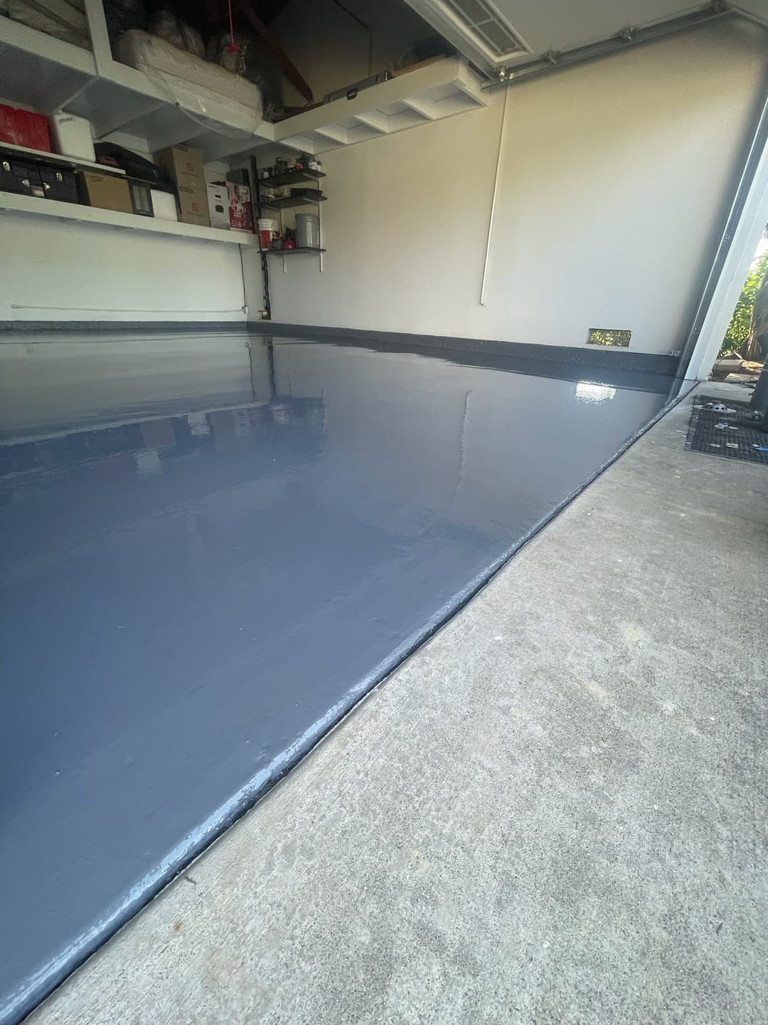 Freshly coated gray epoxy garage floor with a smooth finish and organized storage in the background.