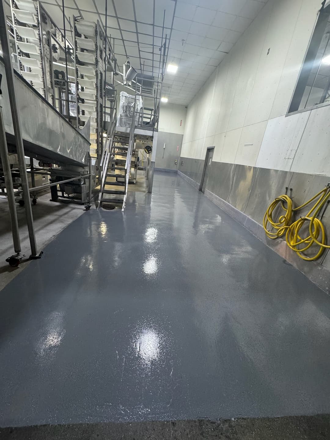 Clean, newly sealed gray epoxy floor in a commercial kitchen with stainless steel equipment.